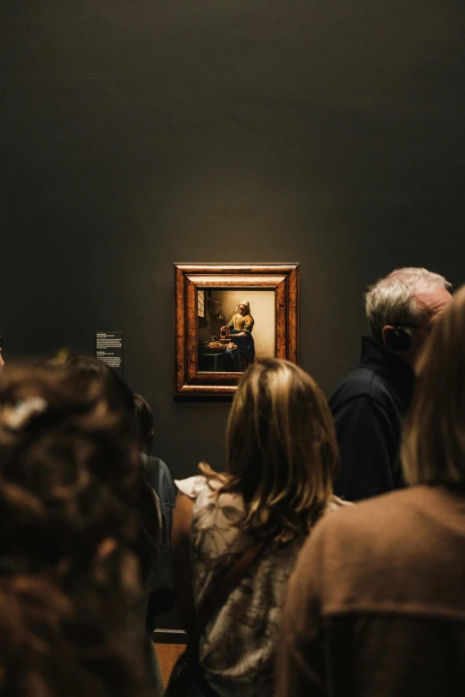 a woman reading a book in front of an art work