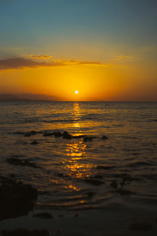 the sun is setting over the ocean and reflecting on the water