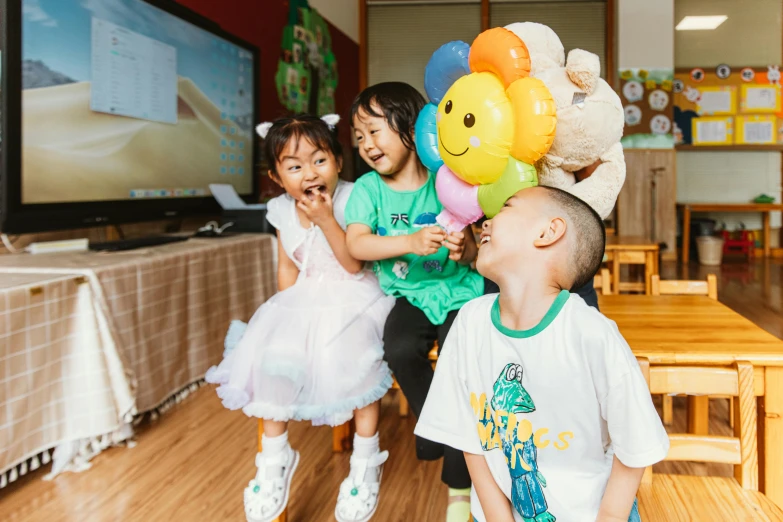 three young children holding up bunches of balloons