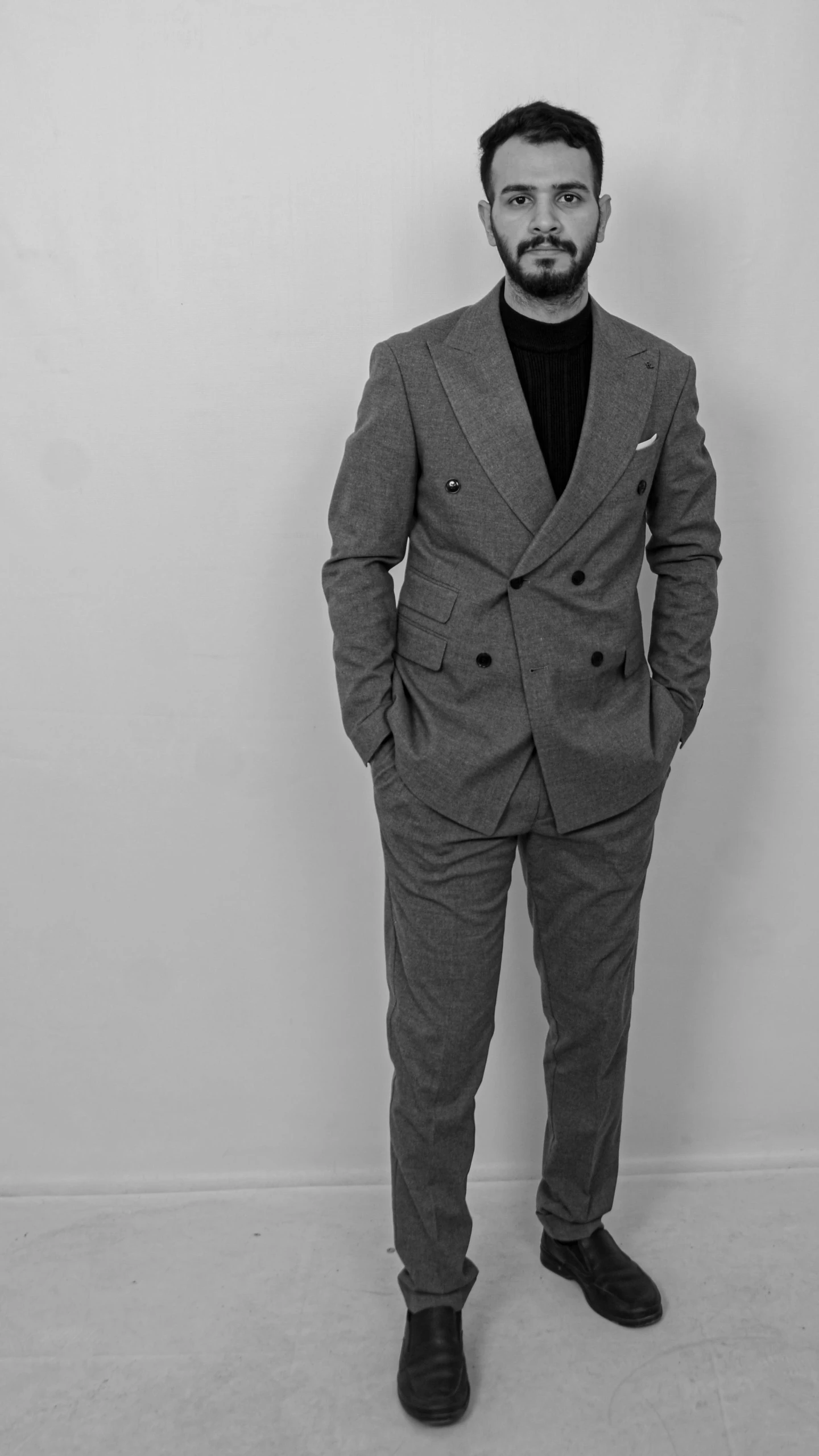a man in a suit poses for a black and white po