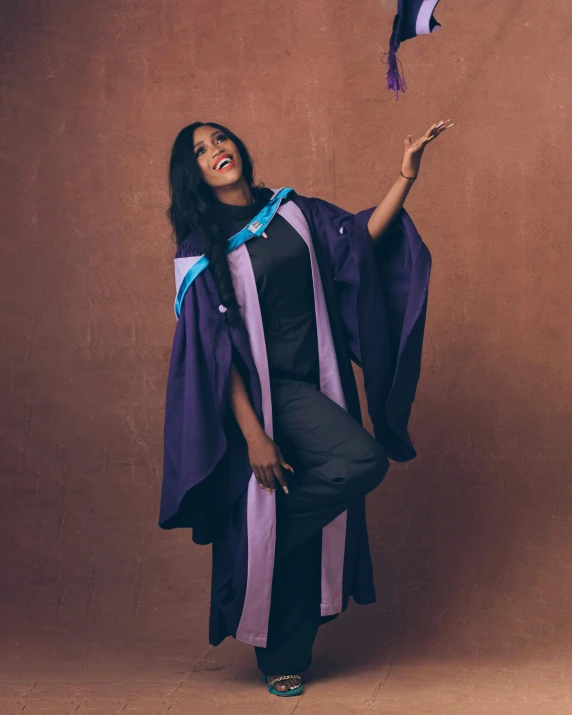 young woman dressed in purple and black standing with her hands raised