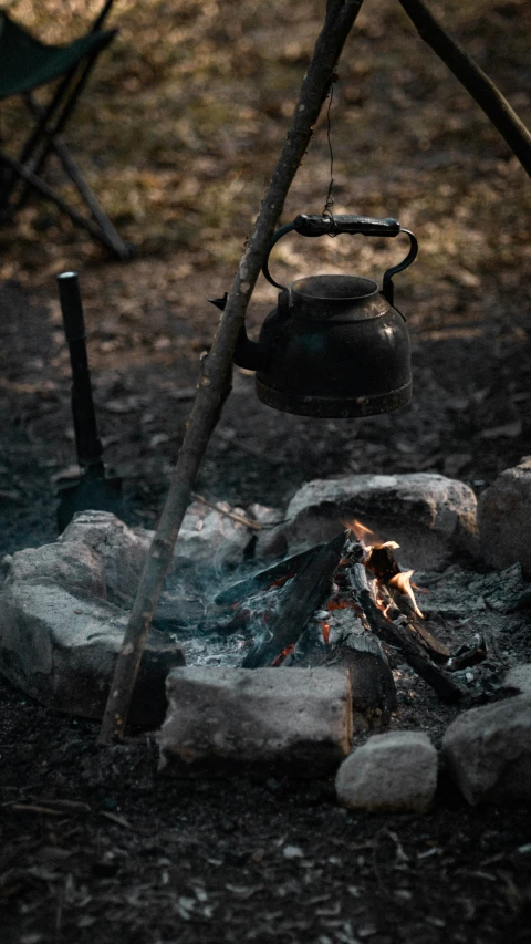 two pot next to a campfire on a forest floor