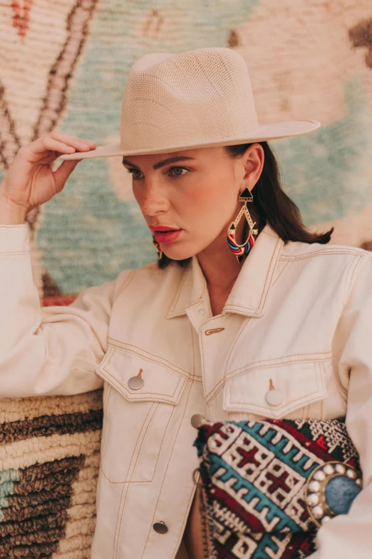 a woman in white cowboy hat standing near a wall