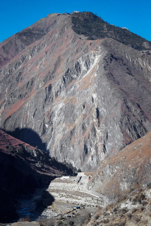 the sun is shining on a mountain with a river running past it