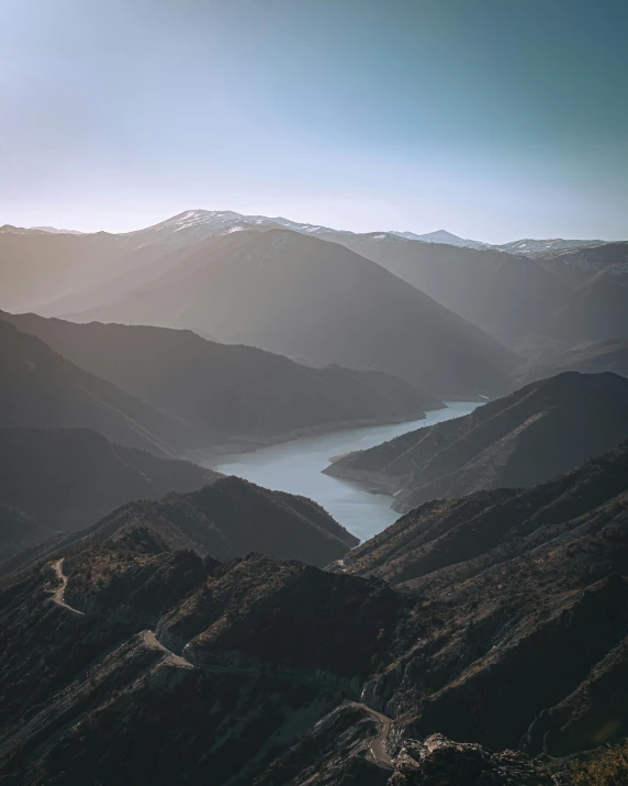 a winding road through the mountains towards the water