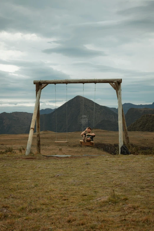 a person on a bench swing set in the middle of a field