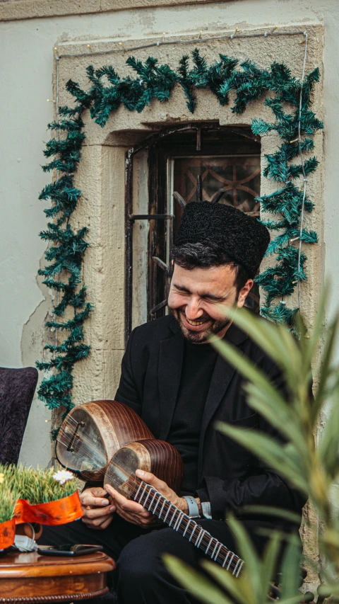 a man playing a guitar with a fake tree