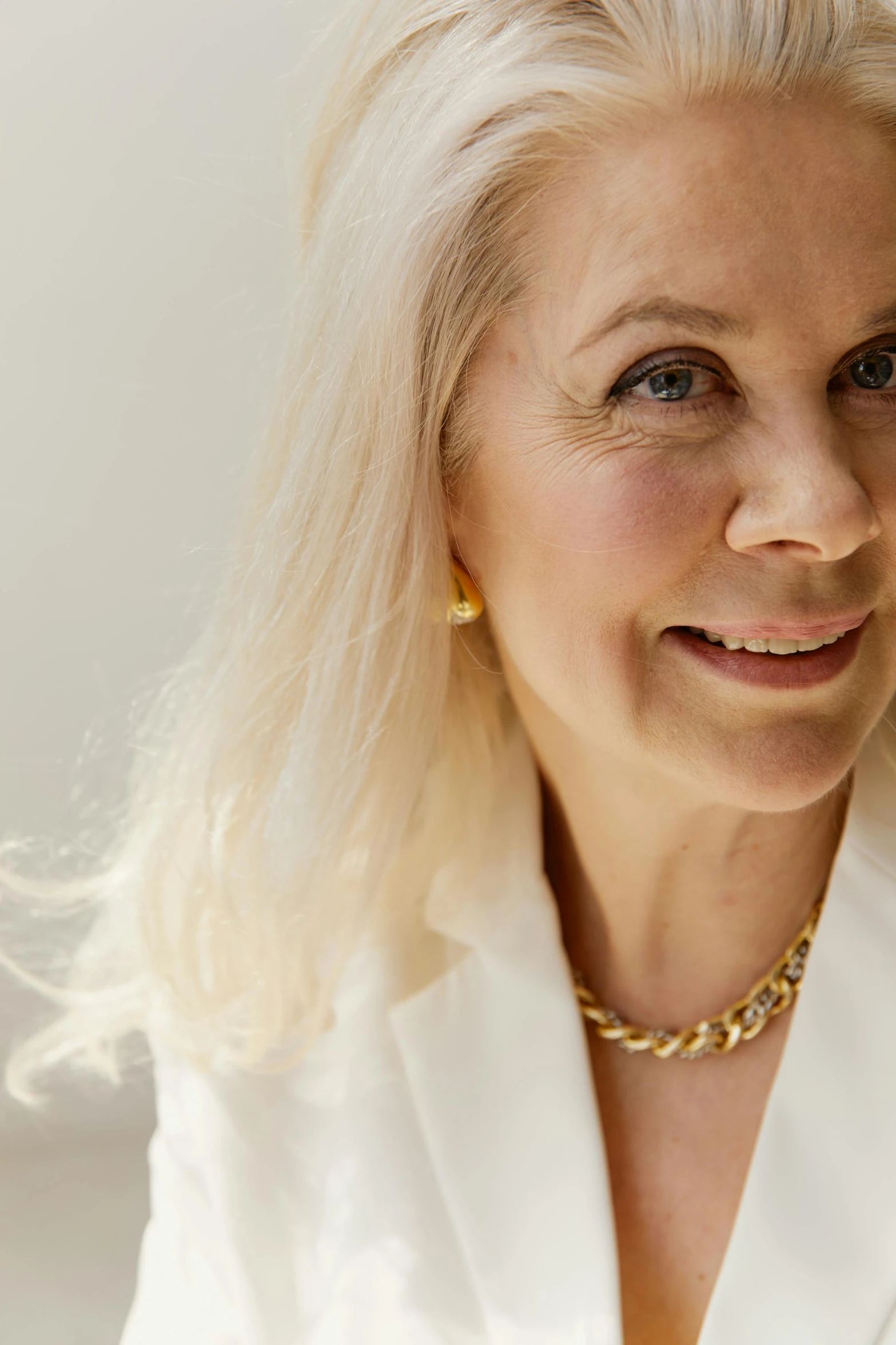 a blonde woman is smiling while wearing jewelry