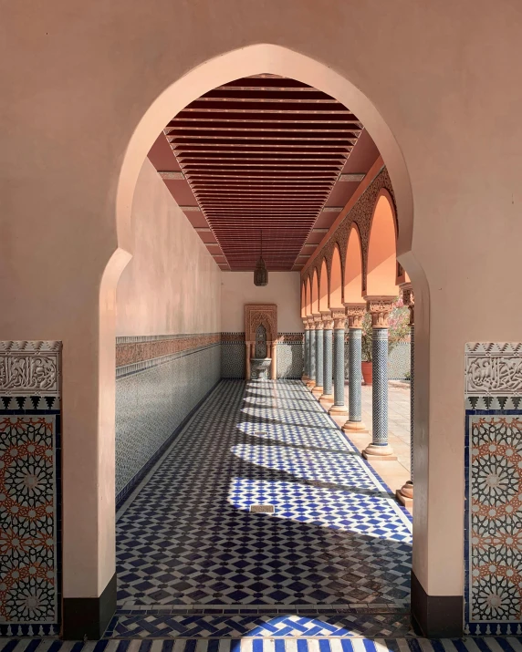 a hallway with many pillars and tiles at the end