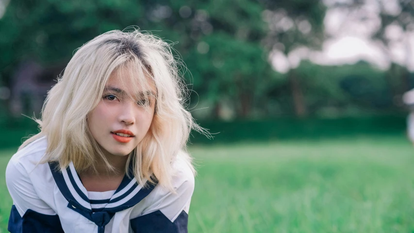 a young blonde woman posing on a field with her tongue sticking out