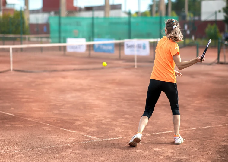 a tennis player in a bright orange shirt is playing tennis