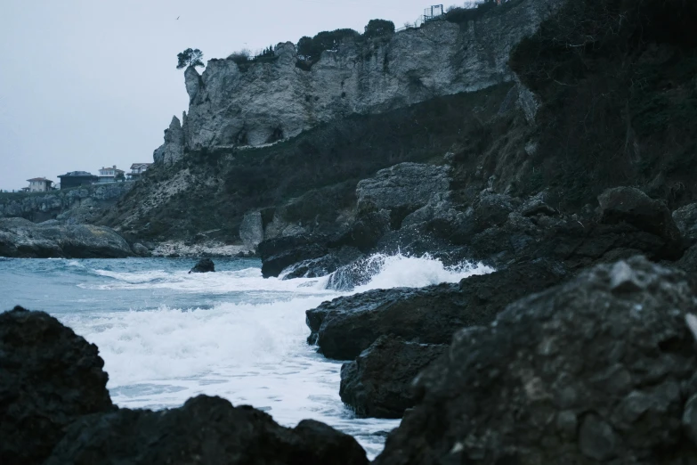 a dark landscape with the ocean crashing under it