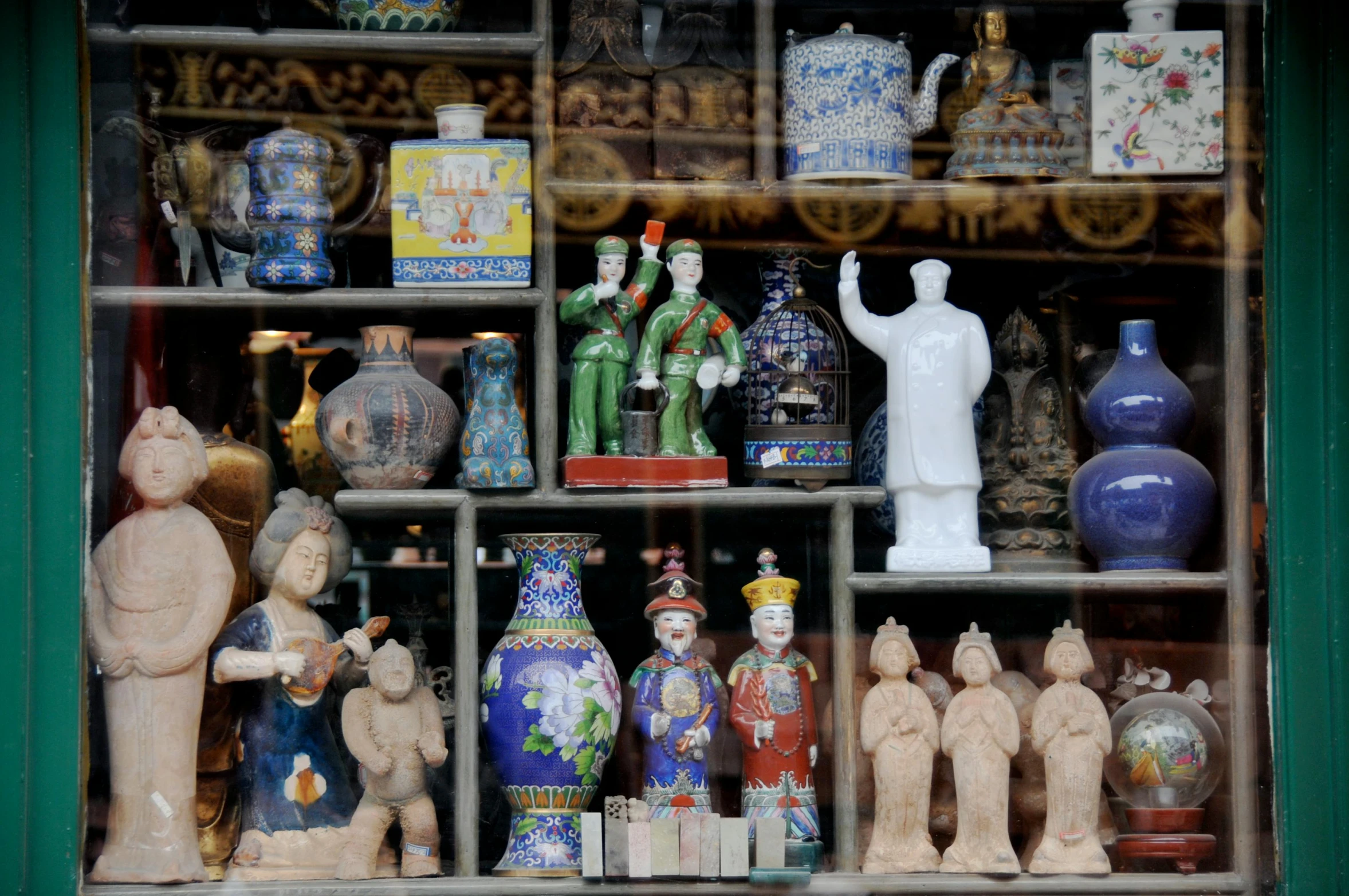 a variety of vases, statues and figurines sitting on a shelf