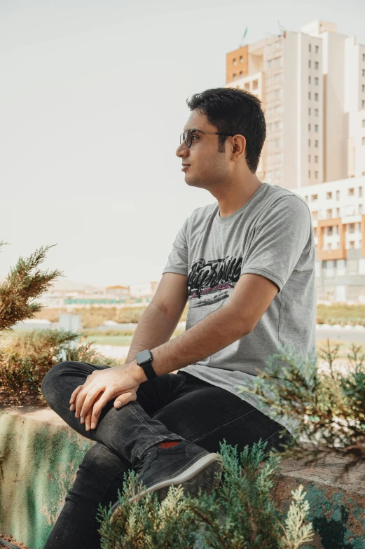 a man sitting down on a stone wall with buildings in the background