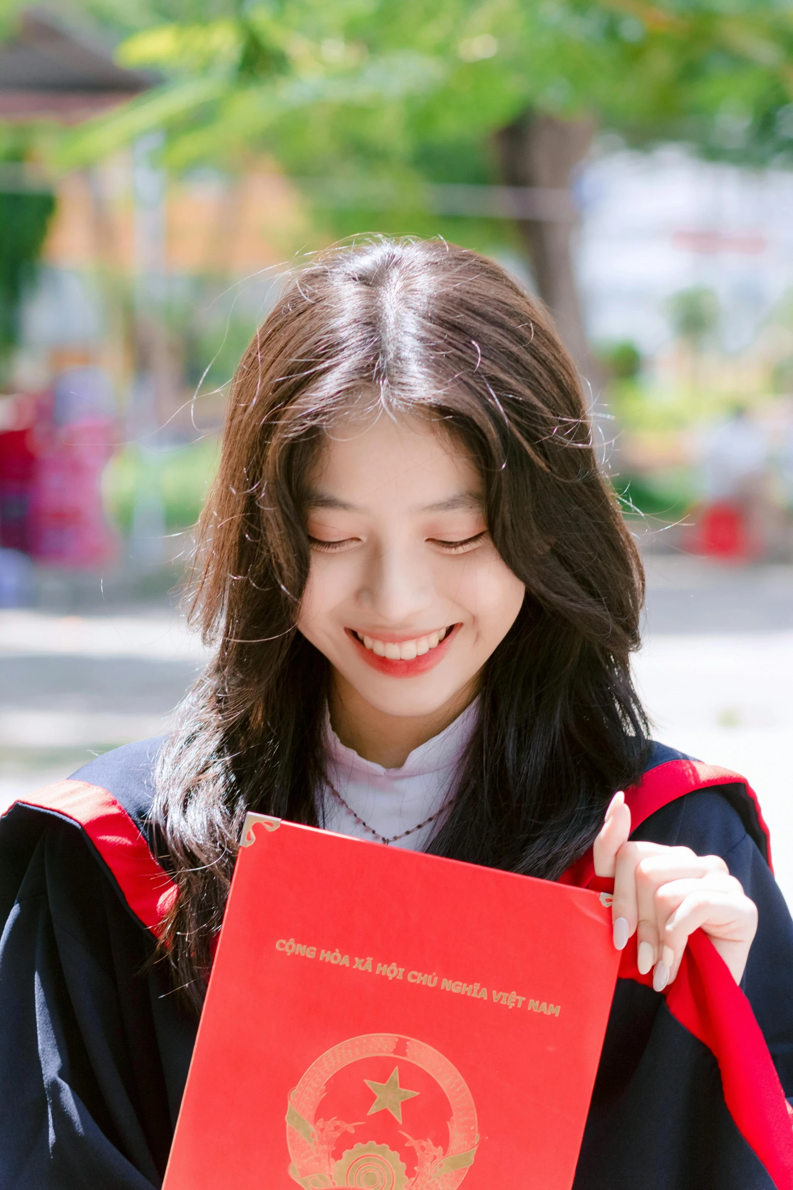 a beautiful young lady in a graduation gown holding a red book