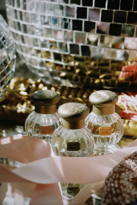 three small, brown, glass bottles with labels on them and pink ribbon