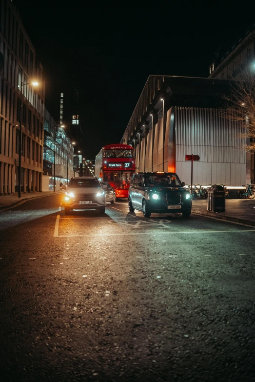 cars on a city street next to tall buildings at night