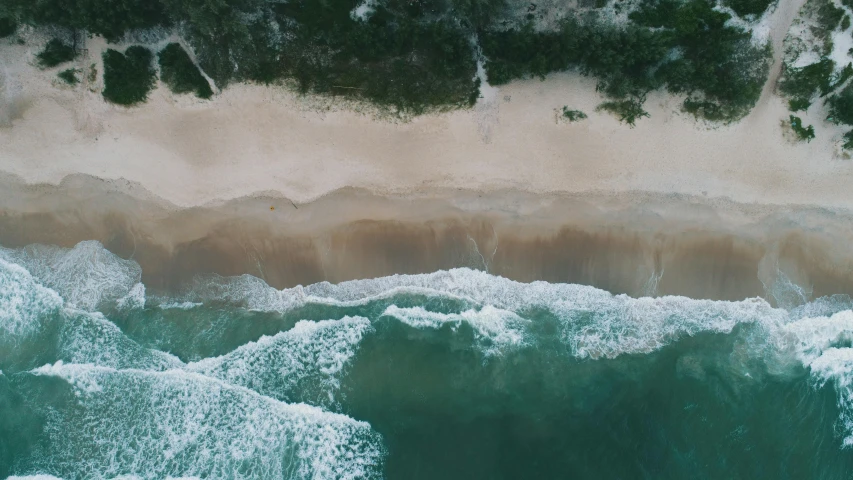 an aerial po of waves on the ocean shore