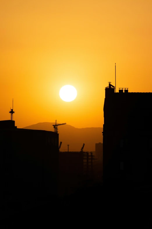 the sun rises over a building silhouette in this po