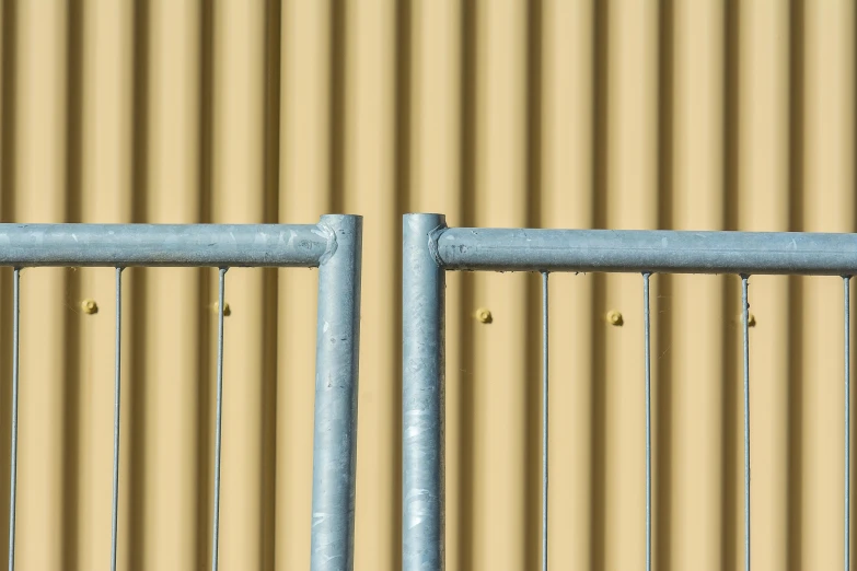 a yellow wall has some blue metal bars and the top of it