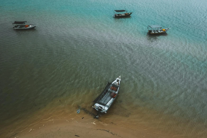 four boats sit in shallow water off the shore