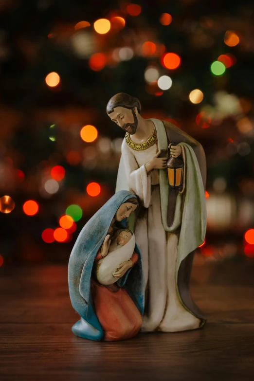 a christmas scene with a nativity statue with a tree in the background