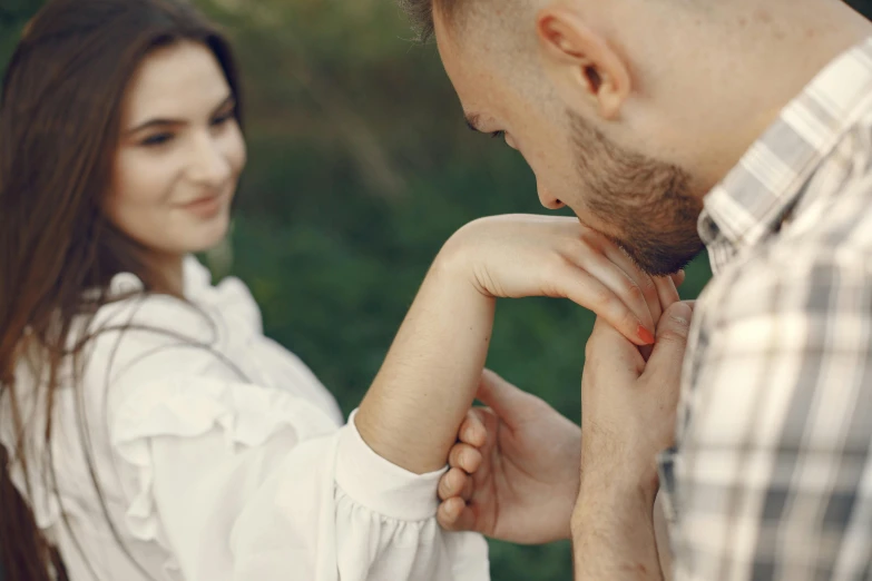 a man and woman facing each other with their hands together