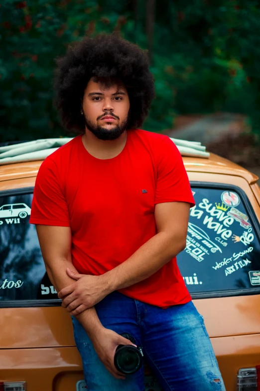 a man in a red shirt is leaning on his car