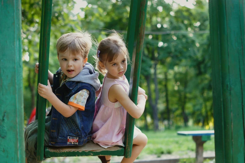 a little girl and boy are playing in a playground