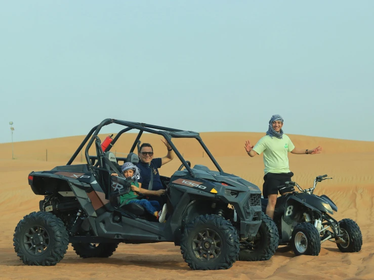 two people are smiling while driving an atv in the sand