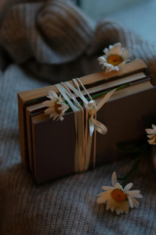 a wrapped book tied up to some daisies