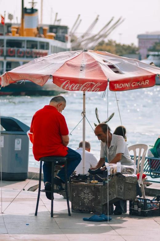 there are some people sitting in chairs under the umbrella