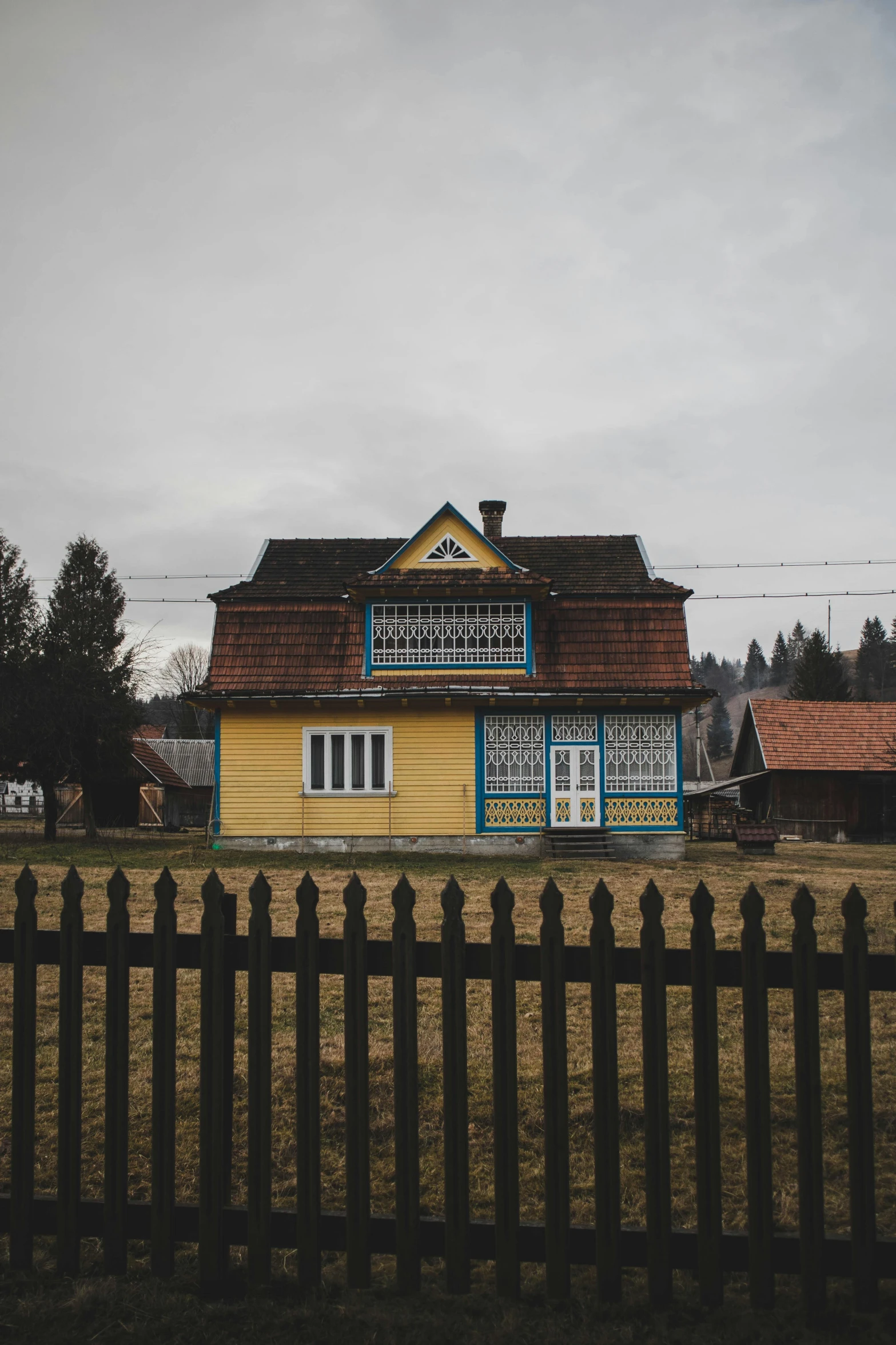 an old yellow house behind a fence