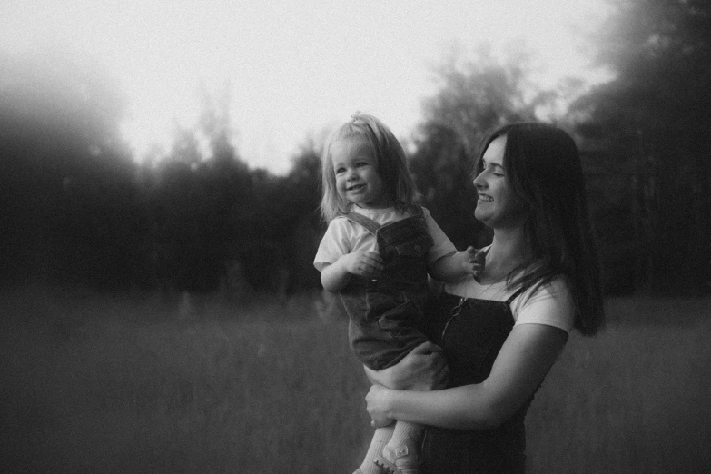 a woman and child looking at each other while standing in front of a tree