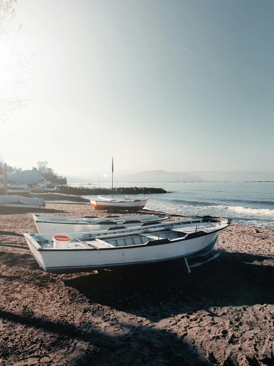 the two boats are on the sand near the water