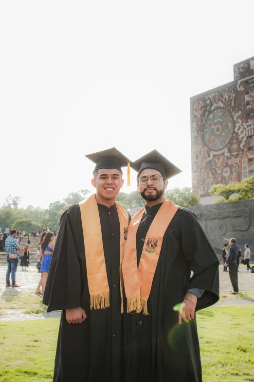 two graduates in caps and gowns posing for a po