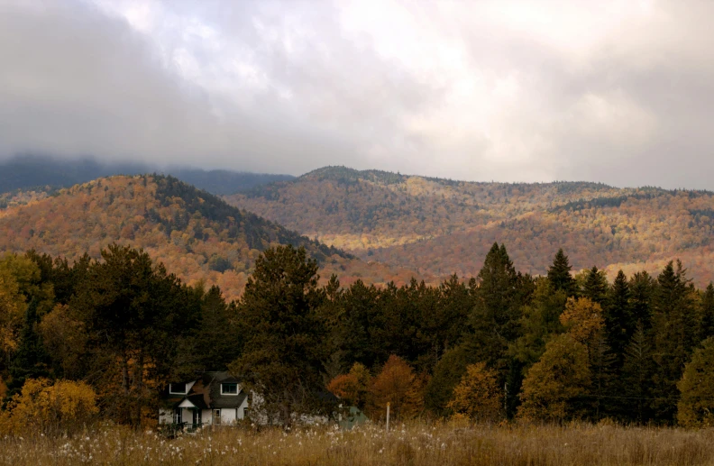 a scenic landscape with mountains and a house surrounded by grass