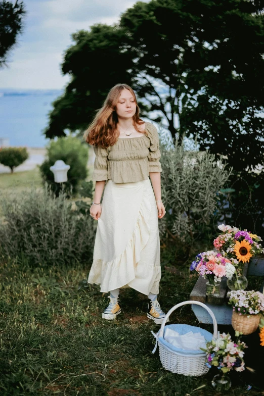 a girl in dress near flowers on grass