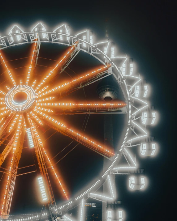 an illuminated ferris wheel at night with buildings in the background