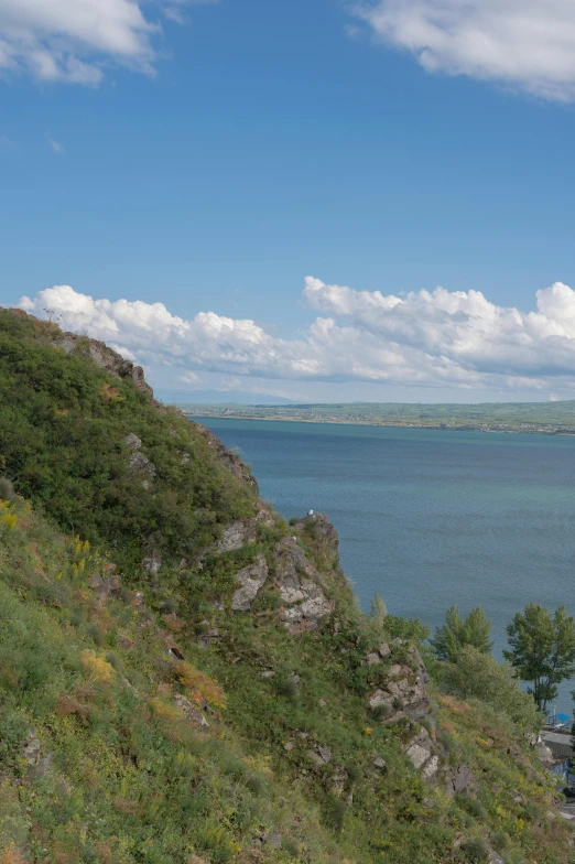 a man with a backpack on top of a mountain by the ocean