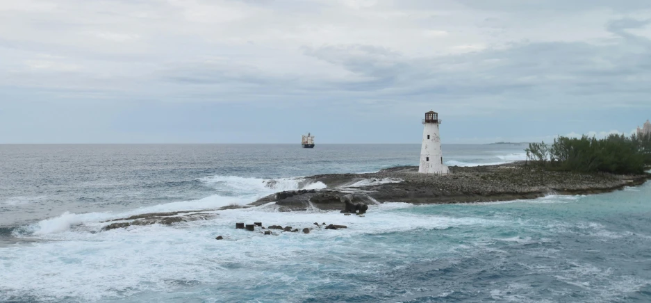 an island with lighthouse in middle water near rocks