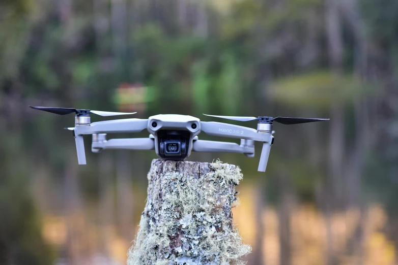 a small white unmanned hovering over a wood post