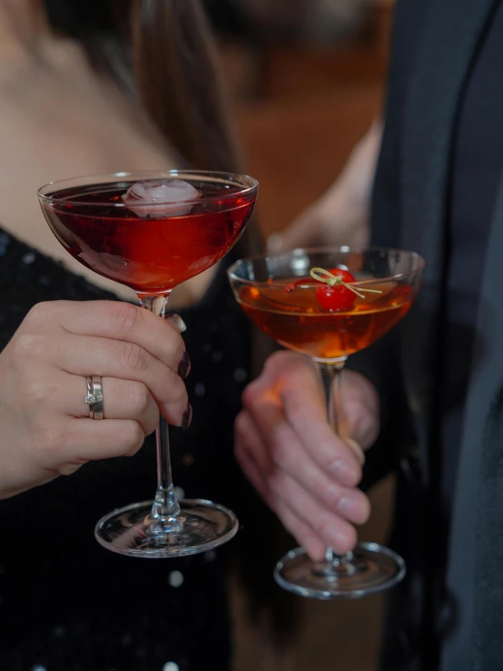 two hands holding wine glasses with different drinks