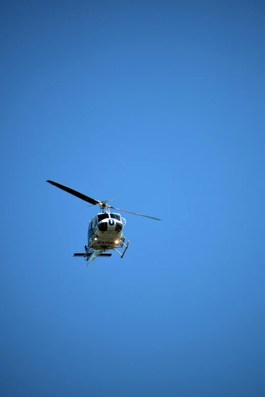 a helicopter flies through the sky with its landing gear