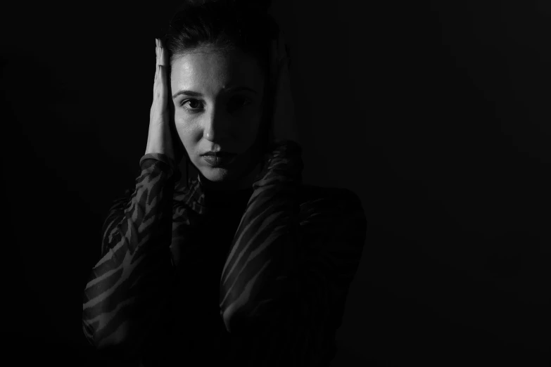 a young woman with dark hair, holding her head against her hand