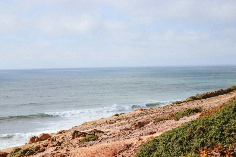 the person is walking up to the beach on his surfboard