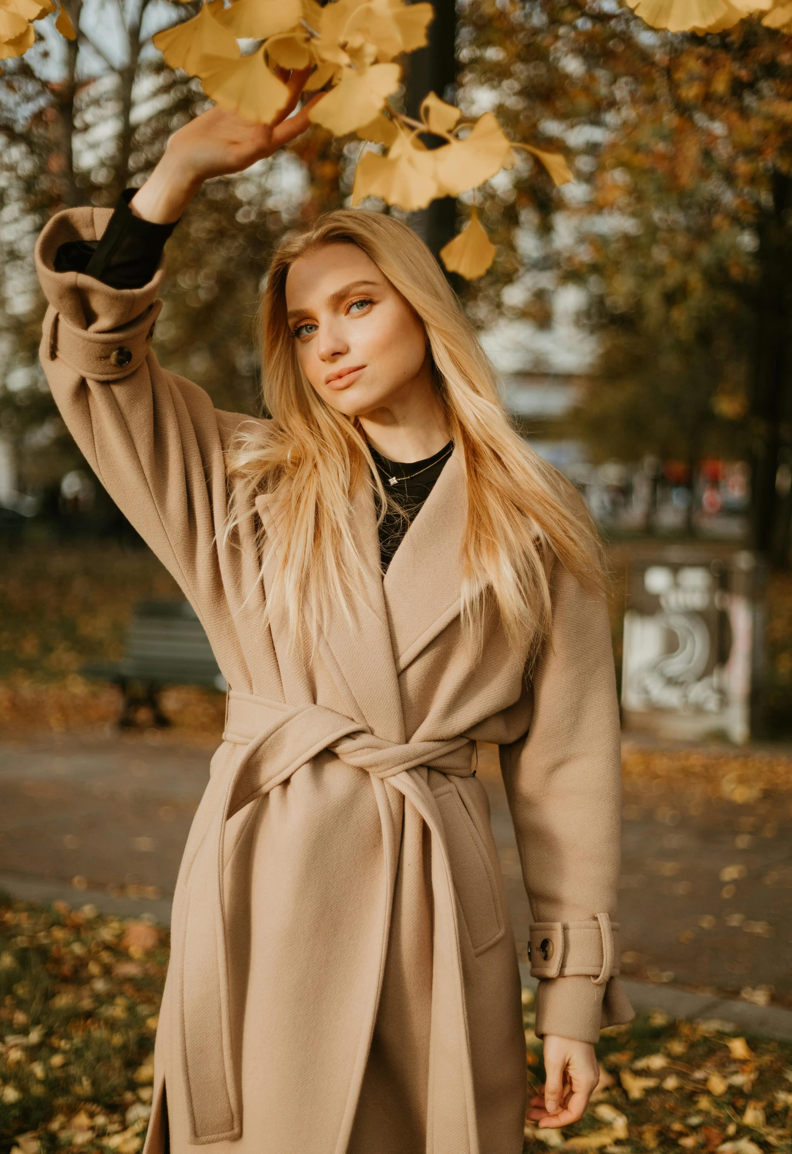 a young woman in an autumn outfit is holding up leaves