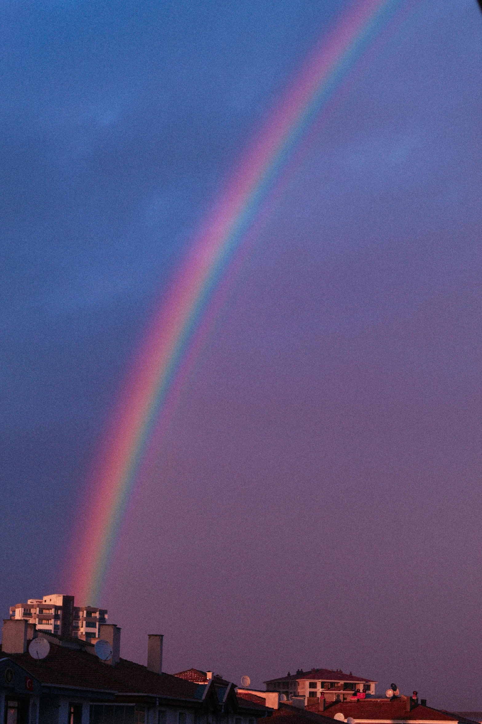 rainbow against blue sky in the city with apartment buildings