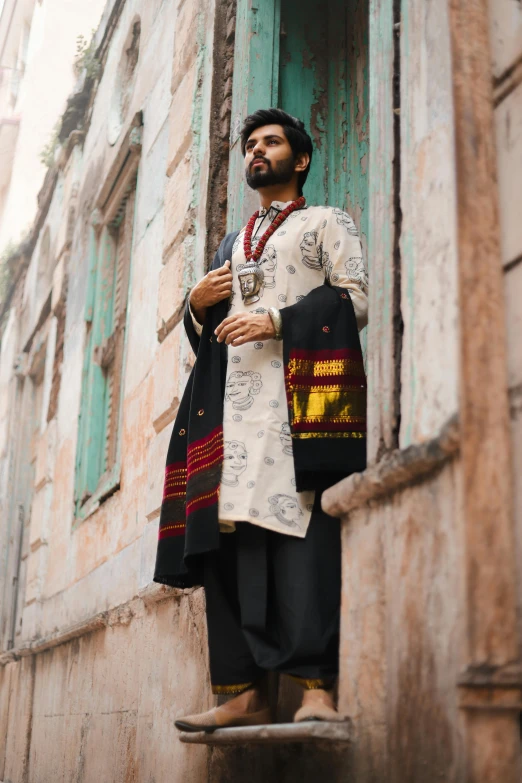 a man is dressed up with a scarf and standing outside a building