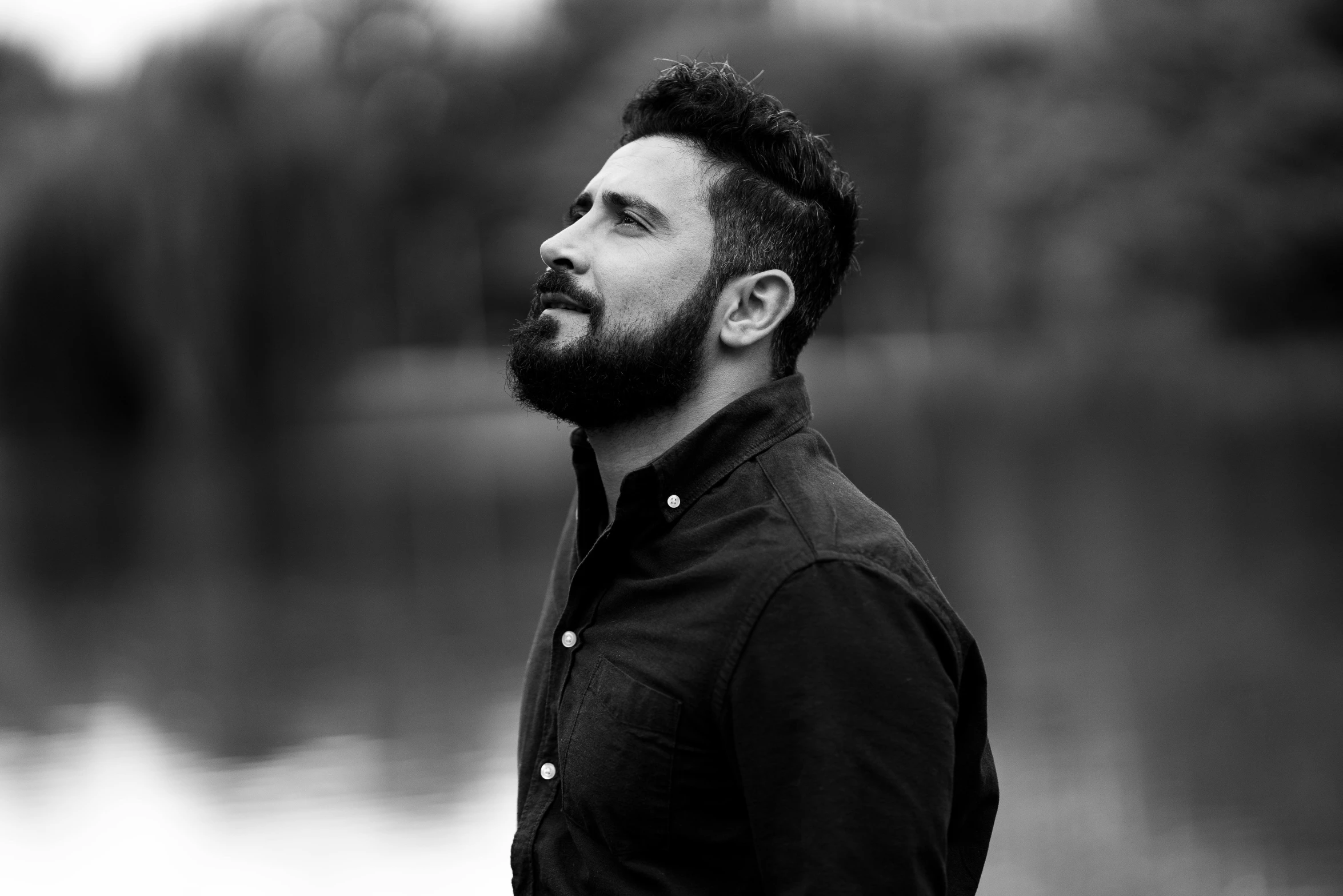 a man standing by a lake looking off in the distance